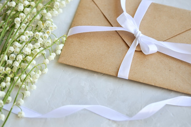 Bouquet of lilies of the valley, craft envelope with a bow on a blue background