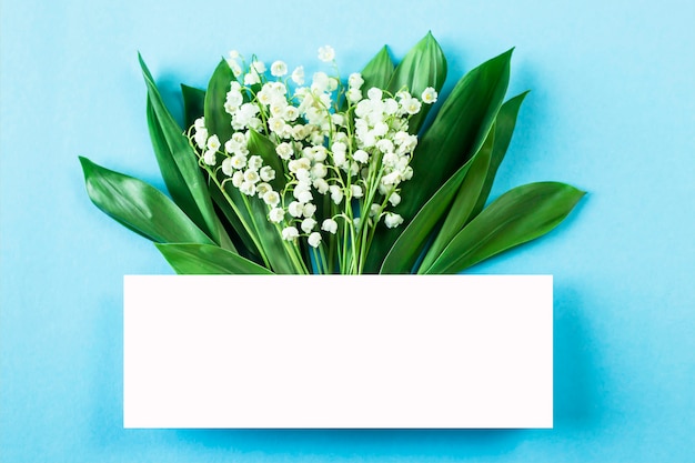 A bouquet of lilies of the valley with a white space for text on a blue background