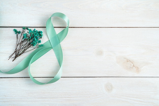 Bouquet and number eight of ribbon on a light wooden background. Top view with space to copy.