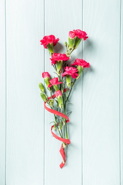 Bouquet of pink carnation on light turquoise wooden background