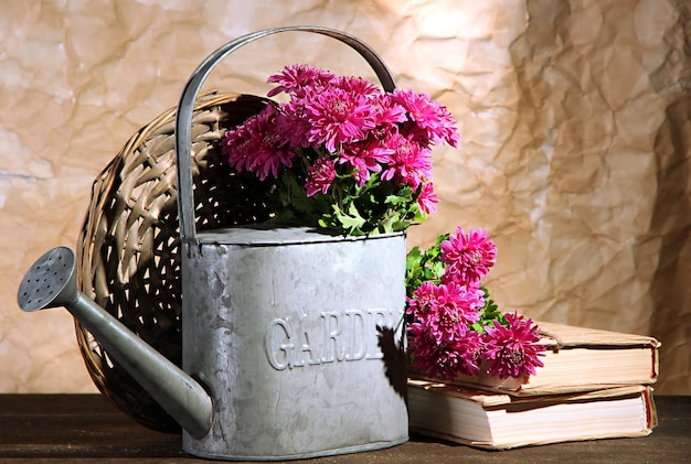 Bouquet of pink chrysanthemum in watering can on wooden table