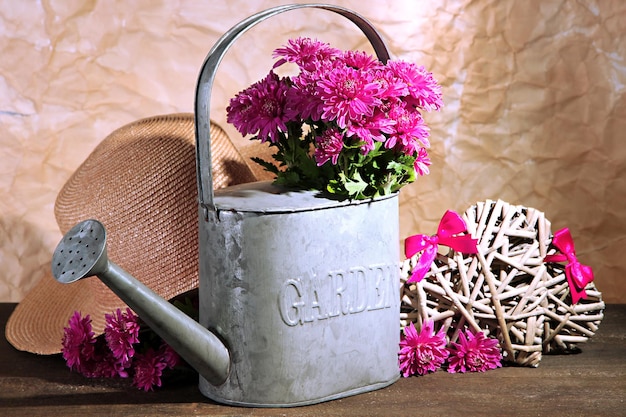 Bouquet of pink chrysanthemum in watering can on wooden table