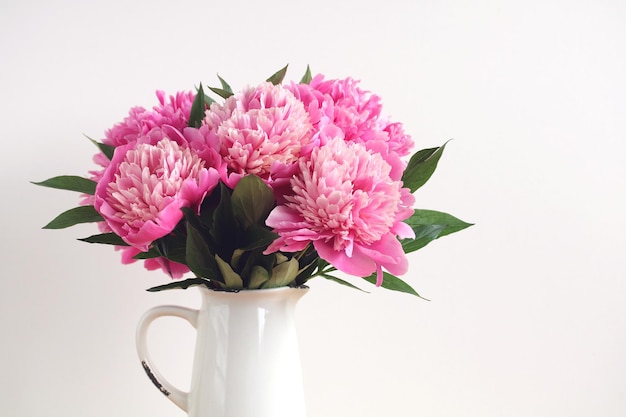 A bouquet of pink peonies in closeup isolated on a white background Garden flowers in a jug