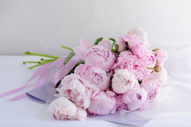 A bouquet of pink peonies lies on the table.