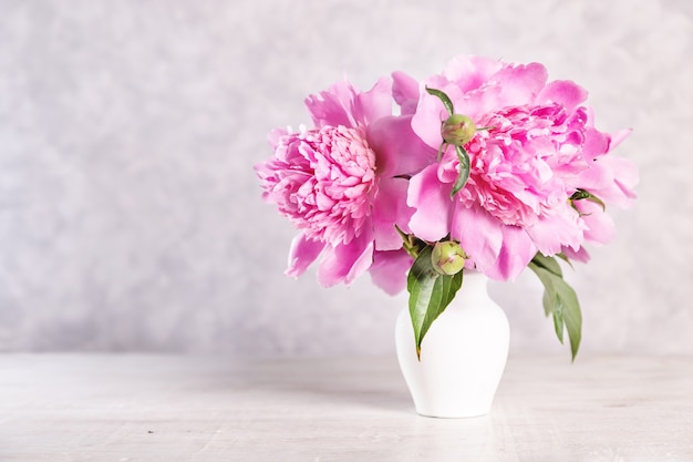 Bouquet of pink peonies in a vase on a wooden table. Gift Valentine's Day.