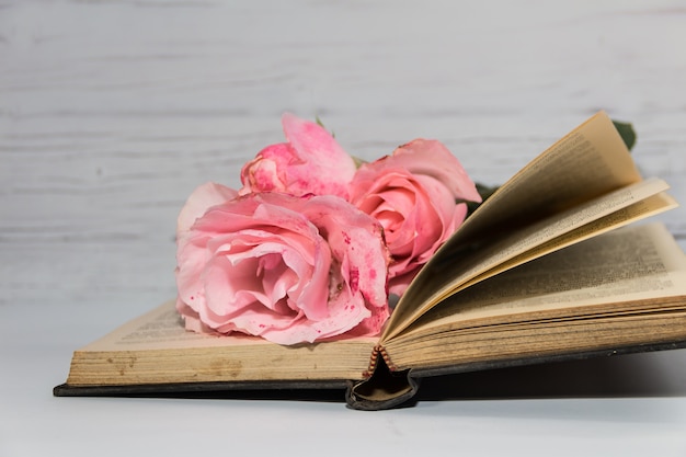 A bouquet of pink roses and books on rustic wood