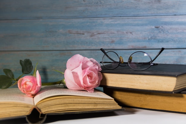 A bouquet of pink roses and books on rustic wood