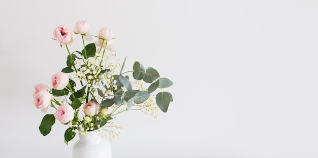 Bouquet of pink roses in ceramic white vase on white background