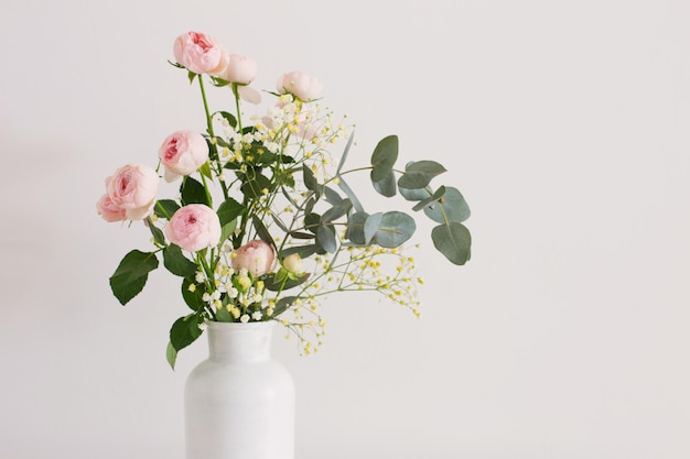 Bouquet of pink roses in ceramic white vase on white background