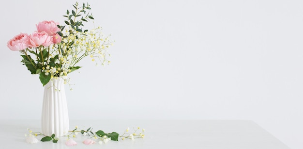 Bouquet of pink roses in ceramic white vase on white background