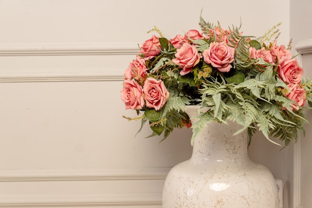 Bouquet of pink roses in floor ceramic vase in classic style. Shbby chic interior decoration.