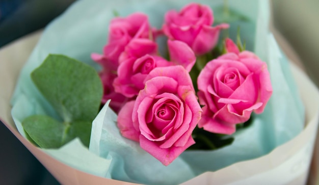 A bouquet of pink roses is displayed in a shop window.