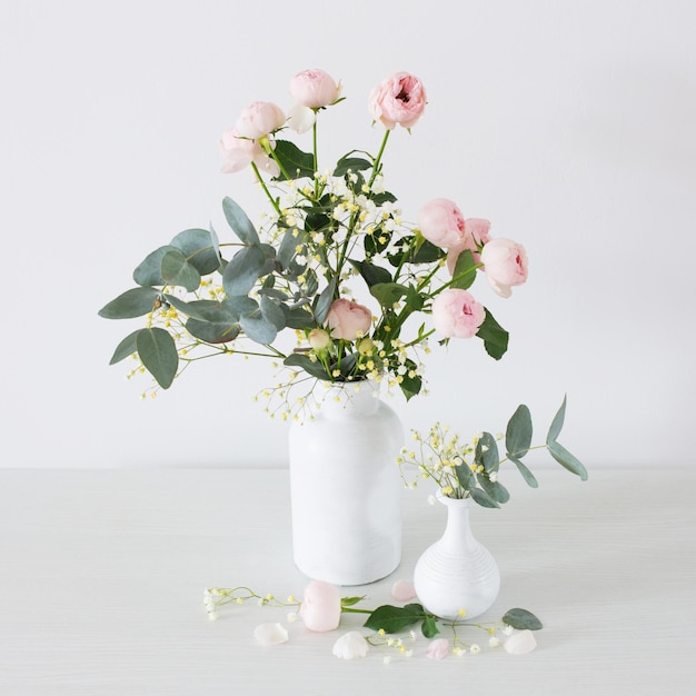 Bouquet of pink roses in two white vases on white background