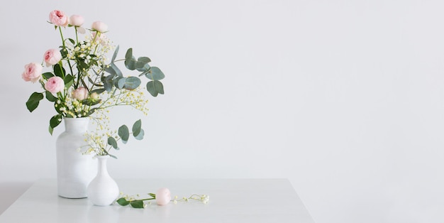 Bouquet of pink roses in two white vases on white background