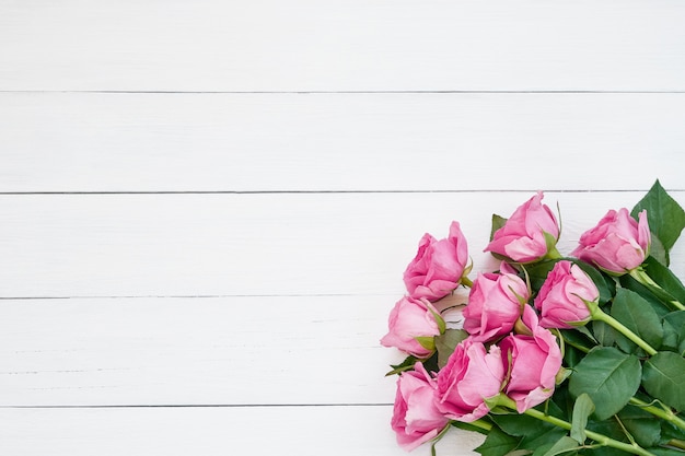 Bouquet of pink roses on white wooden background. Top view, copy space.