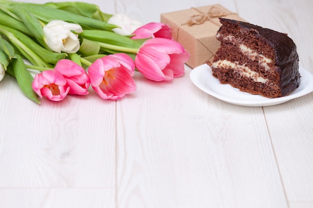 Bouquet of pink tulips, chocolate cake. present box. Copy space, close up. Mother's day concept.