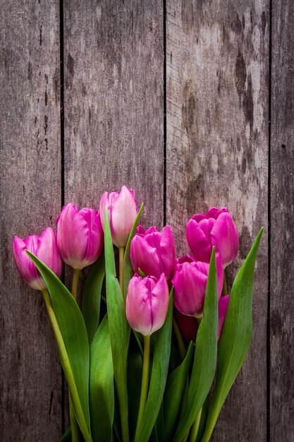 Bouquet of pink tulips on a rustic wooden background