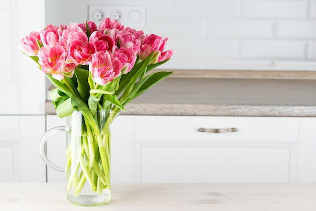 Bouquet of pink tulips in a vase on the kitchen table