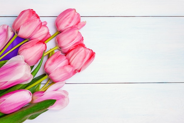 Bouquet of pink tulips with purple ribbon on white background