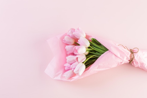 Bouquet of pink tulips wrappen in pink paper.