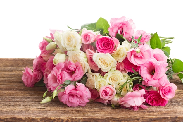 Bouquet of pink and white fresh roses and eustoma on wood border isolated