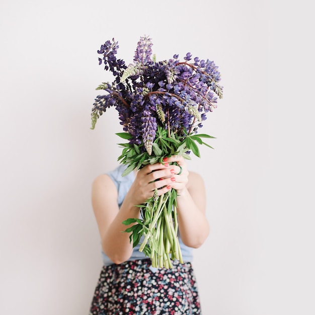 Bouquet of purple lupins in women hands on white surface Florist minimal concept 