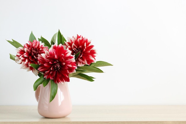 Bouquet of red dahlias in a jug on the table