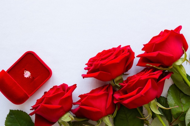 Bouquet of red roses and a wedding ring on white