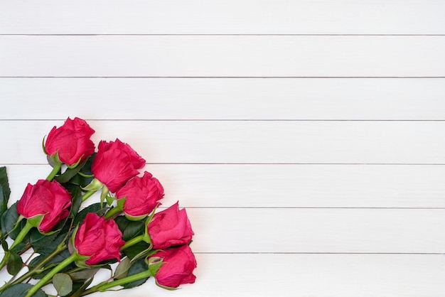 Bouquet of red roses on white wooden background. Top view, copy space