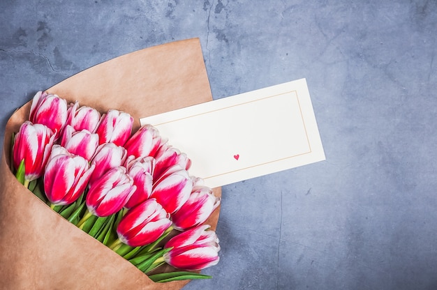 Bouquet of red tulips for a holiday women's day and valentine's day against a gray textured wall.