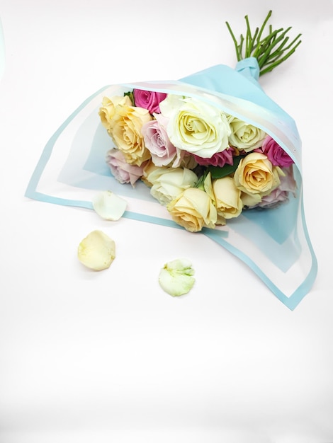 A bouquet of roses is wrapped in a blue paper.