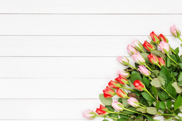 Bouquet of small roses on white wooden background. Top view, copy space