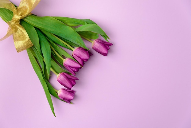 Bouquet of spring tulips in purple color on a purple background top view copy space