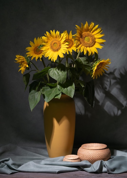 A bouquet of sunflowers in a yellow vase on the floor