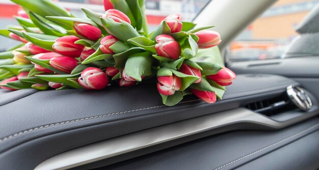 bouquet of tulips in the car interior on the dashboard and on the seat