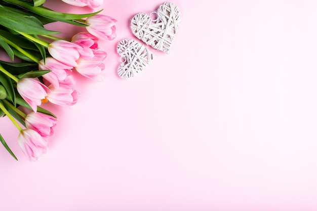 Bouquet of tulips and hearts on pink background. Top view, flat lay style.