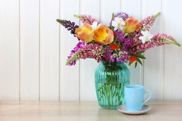 Bouquet of tulips lupines and daffodils in a blue glass vase summer rustic composition copy space