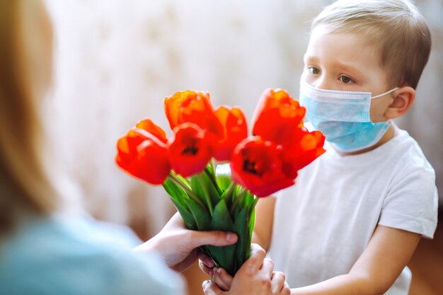 Bouquet of tulips for mom Little son congratulates mother and gives a bouquet of tulips Happy mother...