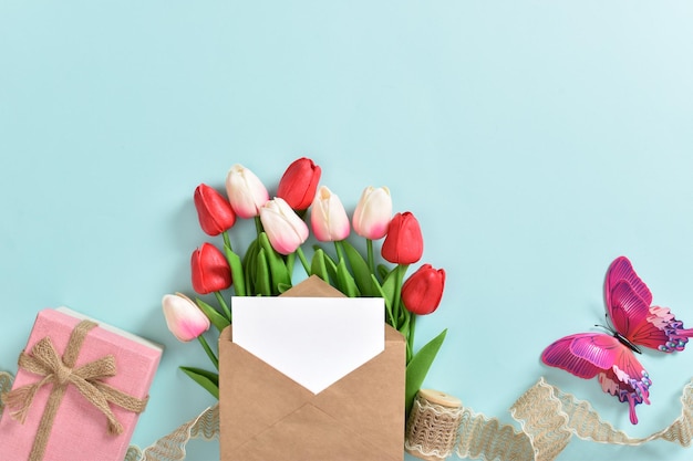 A bouquet of tulips with a postcard and a gift on a light blue background