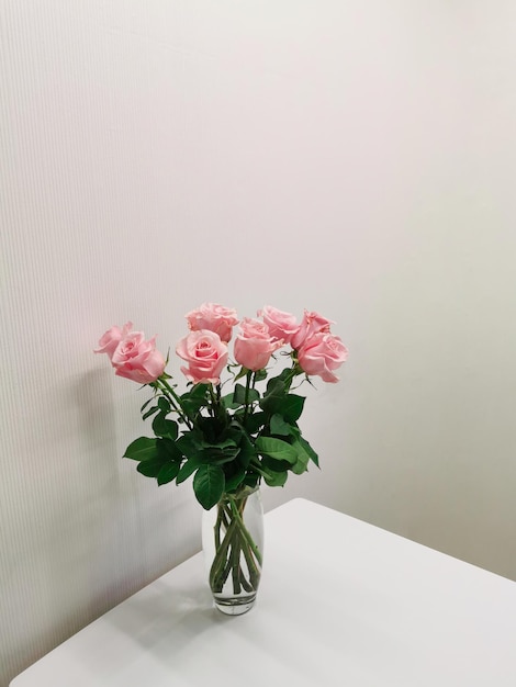 Bouquet in a vase of pink roses on a table in a minimalist white kitchen