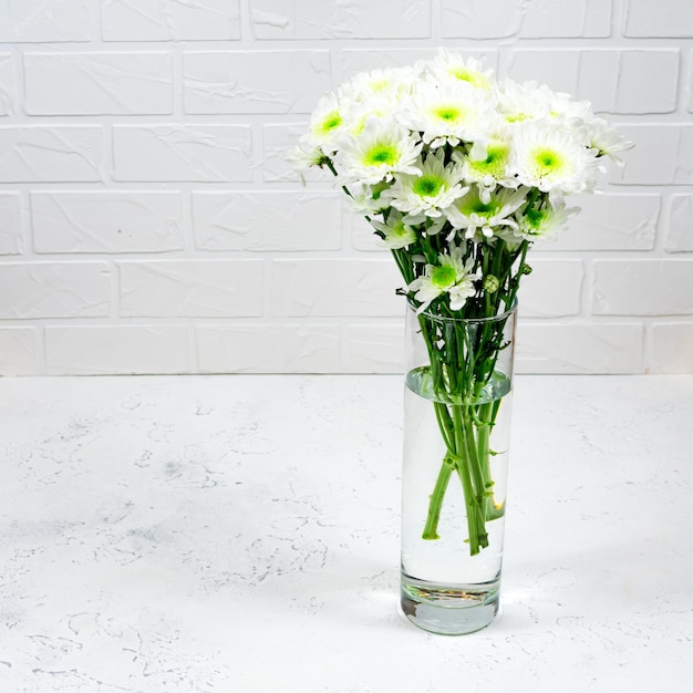 Bouquet of white chrysanthemums in a glass vase on a white background and a wooden table Mother's day card Beautiful chrysanthemum flowers for an online store Flower shop Copy space