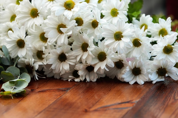 A bouquet of white chrysanthemums lies on a wooden table