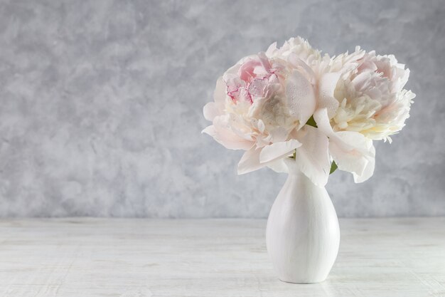 Bouquet of white peonies in a vase on a wooden table. Gift Valentine's Day.