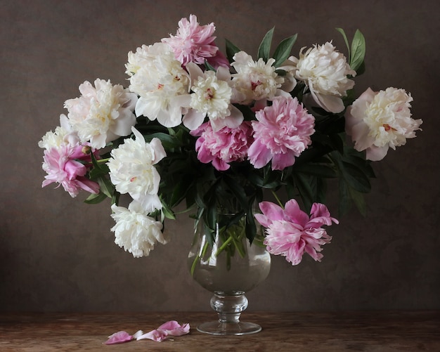 A bouquet of white and pink peonies in a large glass vase