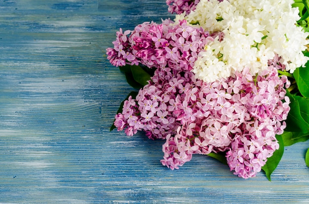 Bouquet of white and purple lilac branches on wooden table