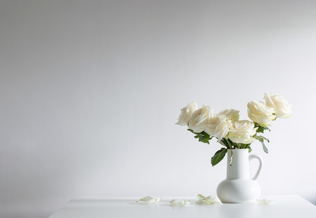 Bouquet of white roses in jug on white background