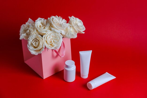 Bouquet of white roses white tube cosmetics on red background cosmetic natural