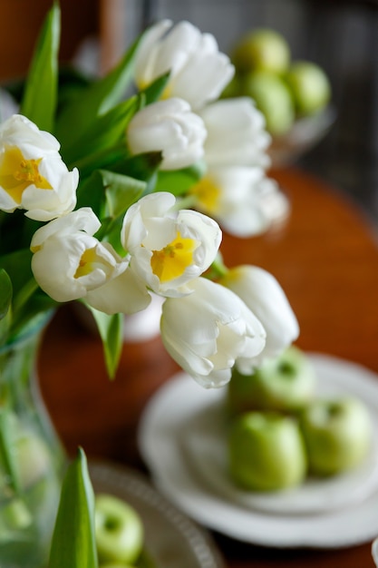 Bouquet of white tulips on a background of green apples