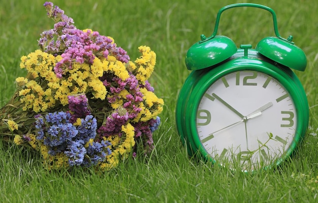 bouquet of wild flowers and an alarm clock on the grass