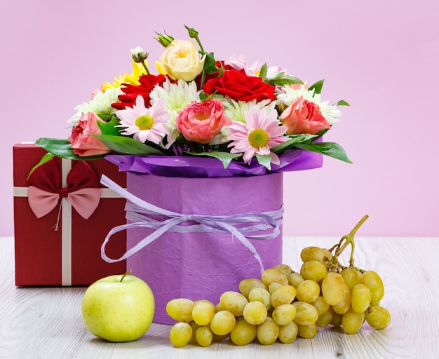 Bouquet of wildflowers, gift box, grapes and an apple on the wooden boards